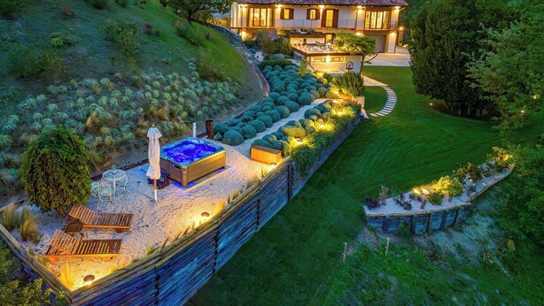 Propiedad en una ladera con jacuzzi, mobiliario de exterior y un jardín bien cuidado.