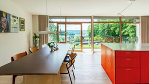 A modern kitchen with a large island, wooden dining table, and chairs. - Designer villa in Laven near Himmelbjerget (Silkeborg)