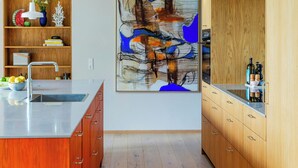 A modern kitchen with wooden cabinets, a central island, and a large abstract painting on the wall. - Designer villa in Laven near Himmelbjerget (Silkeborg)