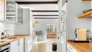 Une cuisine moderne avec des meubles blancs, un plancher en bois et un coin repas comprenant une table et des chaises.