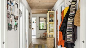 A hallway with a wooden ceiling, a patterned rug, a wicker basket, and a coat rack with various jackets. - Summer house with large nature plot in Rørvig (Rørvig)