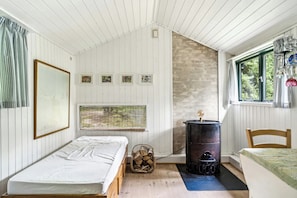 Eine Hütte mit einem Bett, einem Vorhangfenster, einem Kamin und einer Wand mit gerahmten Bildern.