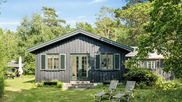 A wooden cabin with a porch, a lawn, and a chair. - Summer house with large nature plot in Rørvig (Rørvig)