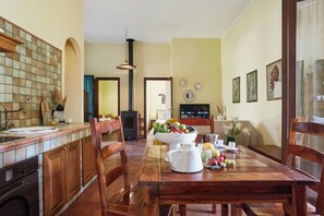 Eine Küche mit Holztisch, gedecktem Esstisch, Herd und Essbereich mit Stühlen.