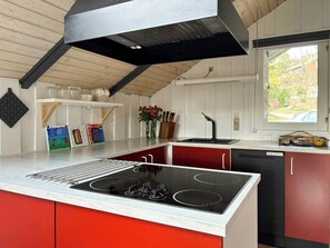 A modern kitchen with a gas stove, a sink, and a window with a view of the outdoors. - Summer house on natural plot with three terraces (Ebeltoft)