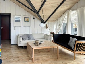 A living room with a sofa, a coffee table, and a wooden floor. - Summer house on natural plot with three terraces (Ebeltoft)