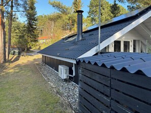 A building with a corrugated metal roof, a chimney, and a window. - Summer house on natural plot with three terraces (Ebeltoft)