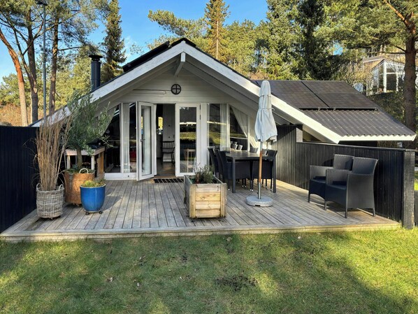 A house with a deck, a covered patio, and a fenced backyard. - Summer house on natural plot with three terraces (Ebeltoft)