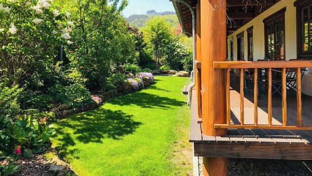 A wooden deck with a stone pathway leading to a building. - Chalet with sauna at Ilsetal in the Harz (Ilsenburg (Harz))
