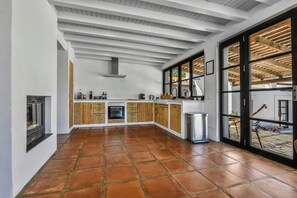 Eine geräumige Küche mit Holzausstattung, einem großen Fenster und einem gefliesten Boden.