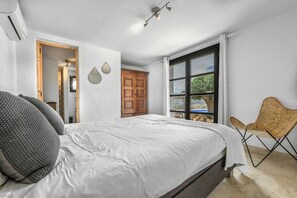 Ein Schlafzimmer mit Bett, einem Fenster mit Blick, einem Holzschrank und einem Stuhl.