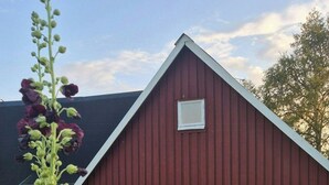 Ein rotes Bauernhaus mit Steinaußenwand, eine Schotterauffahrt und ein Holztisch mit Stühlen.