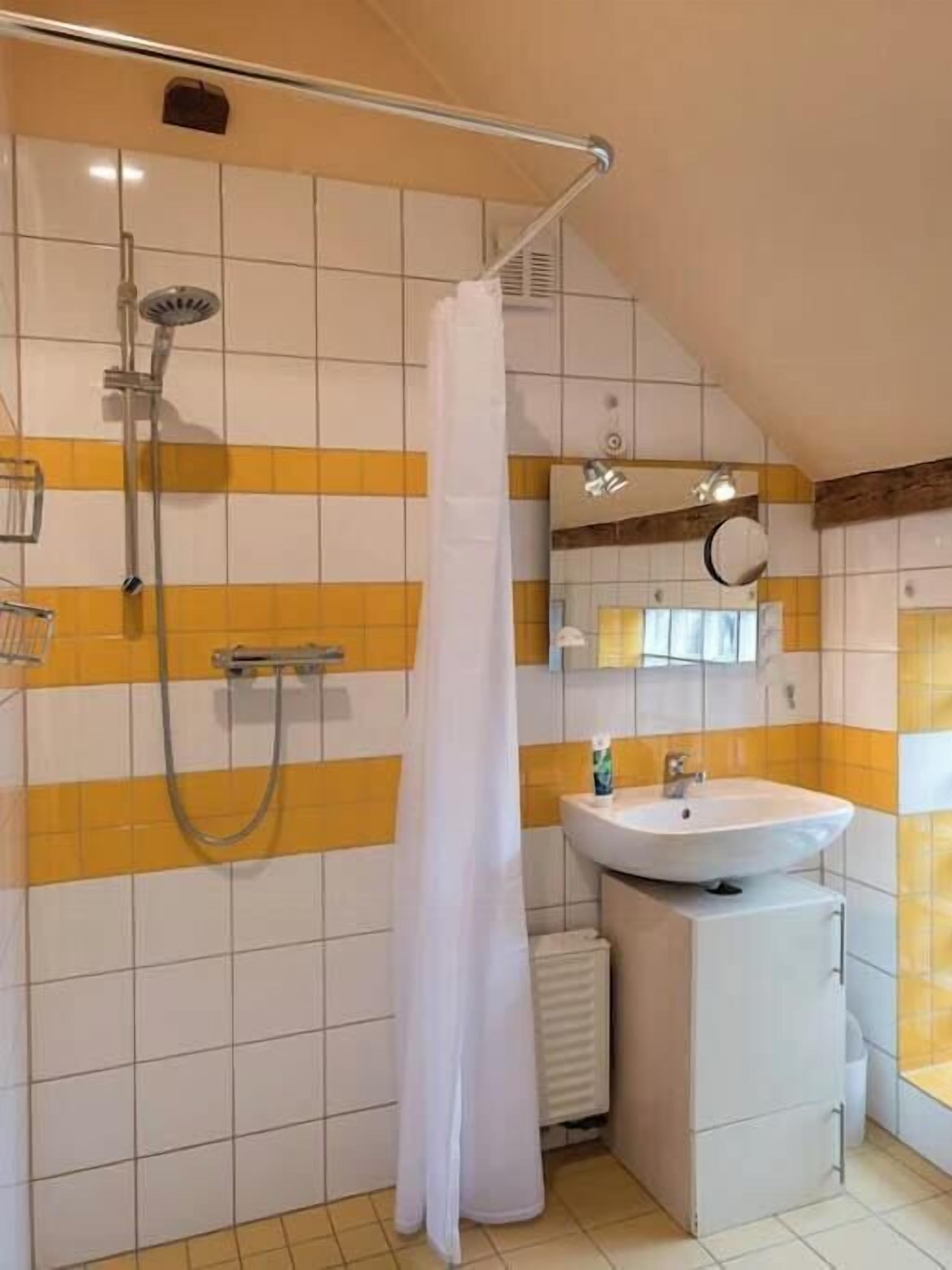 Ein Badezimmer mit Dusche, Waschbecken und Spiegel.