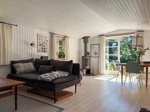 Ein Wohnzimmer mit einer Couch, einem Tisch, einem Kamin und einem Essbereich mit Stühlen.