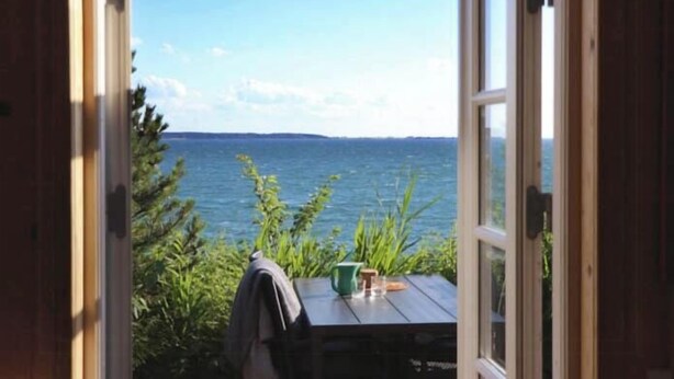 An open door leading to a table with a view of the sea. - "Lærkehuset" right by Kalundborg Fjord (Kalundborg)