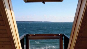 A view from a window with a wooden frame, overlooking a body of water and a distant shoreline. - "Lærkehuset" right by Kalundborg Fjord (Kalundborg)