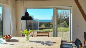 A dining area with a table, chairs, a vase with flowers, and a view of the outdoors. - Peaceful summer house near Limfjorden (Nykøbing Mors)