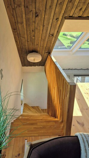 A wooden staircase leading to a loft with skylights, a ceiling light fixture, and a view of greenery outside. - Peaceful summer house near Limfjorden (Nykøbing Mors)