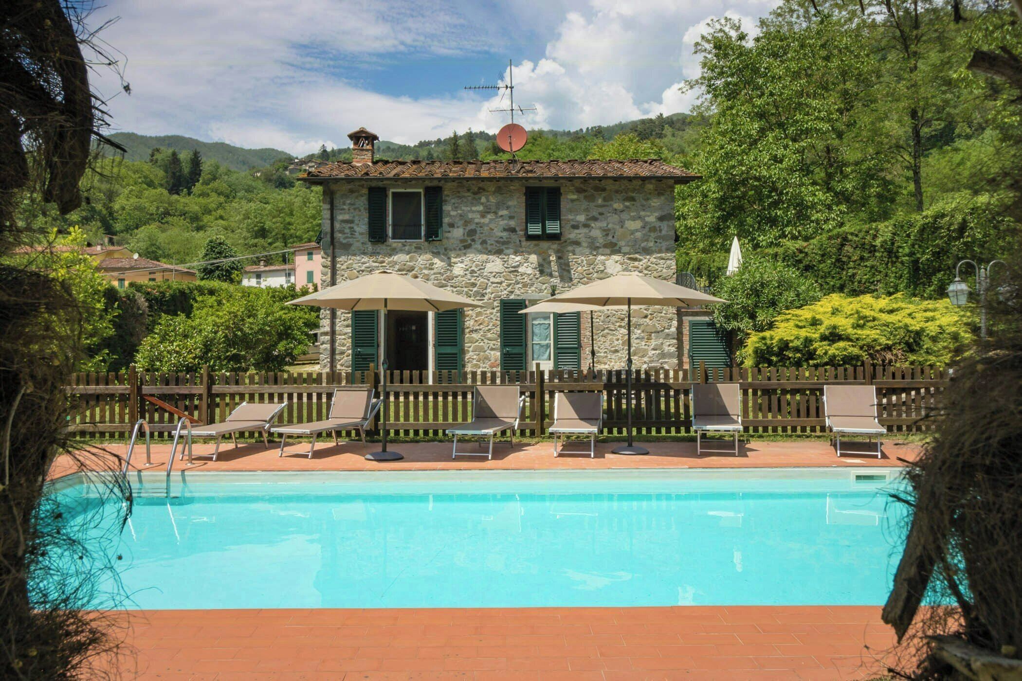 A stone building with a pool, outdoor seating, and a wooden fence.