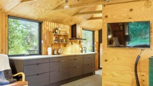 Une cuisine moderne avec des poutres en bois, une grande fenêtre et un téléviseur encastré.
