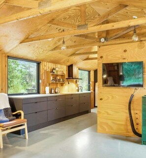 A modern kitchen with wooden beams, a large window, and a built-in TV. - Architect-designed 1960s house near Svinkløv (Fjerritslev)