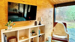 Un intérieur en bois avec un téléviseur, des étagères, une chaise et une fenêtre.