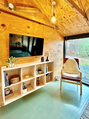 A wooden interior with a TV, shelves, a chair, and a window. - Architect-designed 1960s house near Svinkløv (Fjerritslev)
