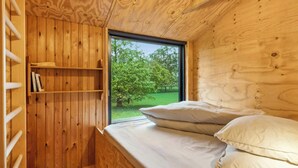 Une pièce de cabane en bois comprenant un lit, une fenêtre et une bibliothèque.