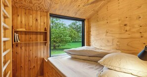 A wooden cabin room with a bed, a window, and a bookshelf. - Architect-designed 1960s house near Svinkløv (Fjerritslev)