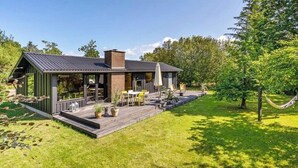 Une maison moderne dotée d’une terrasse, de mobilier d’extérieur et d’un hamac.
