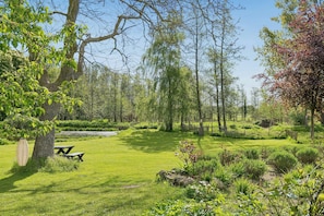En välskött trädgård med ett picknickbord, ett varierat utbud av träd och en klar himmel.