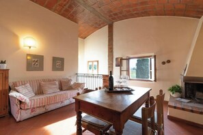 A cozy living room with a sofa, wooden table, and fireplace. - Villa in the farmhouse with pool in Tuscany (Bucine)