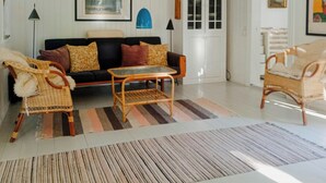 A living room with a sofa, two armchairs, a coffee table, a striped rug, a cabinet, and a painting on the wall. - Retro and simplicity in two small houses by Arresø (Frederiksværk)