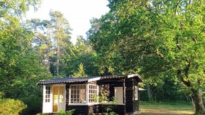 A log cabin with a porch, surrounded by trees. - Retro and simplicity in two small houses by Arresø (Frederiksværk)