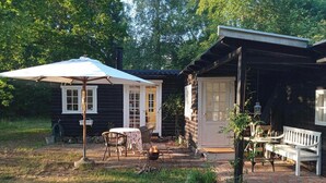 A log cabin with a patio area, outdoor seating, and a fire pit. - Retro and simplicity in two small houses by Arresø (Frederiksværk)