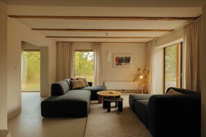 Ein modernes Wohnzimmer mit Ecksofa, rundem Couchtisch und minimalistischer Einrichtung.