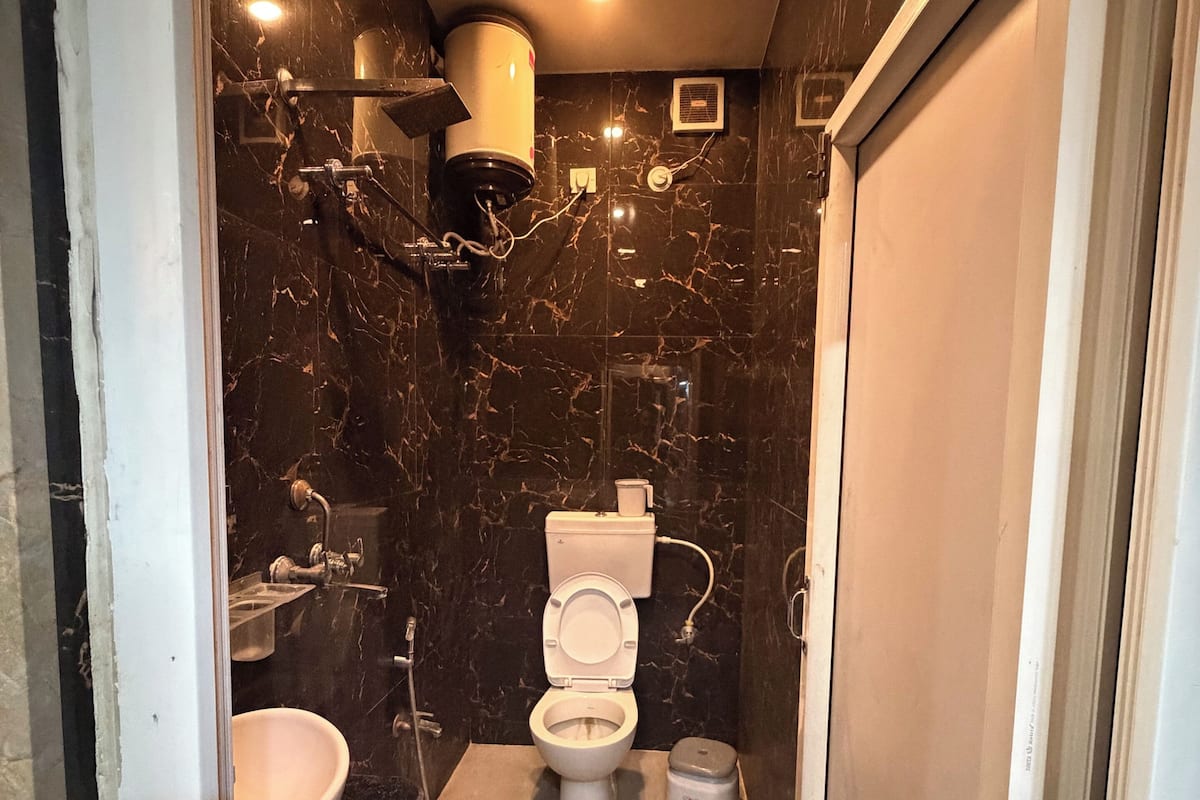 Un baño con pared de mármol, inodoro, lavabo y zona de ducha.