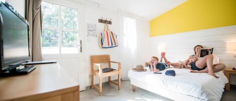 Quarto com cama, escrivaninha, cadeira, televisão e janela.
