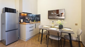 Une cuisine moderne équipée d’un four encastré, d’un évier et d’un coin repas avec une table dressée pour deux personnes.