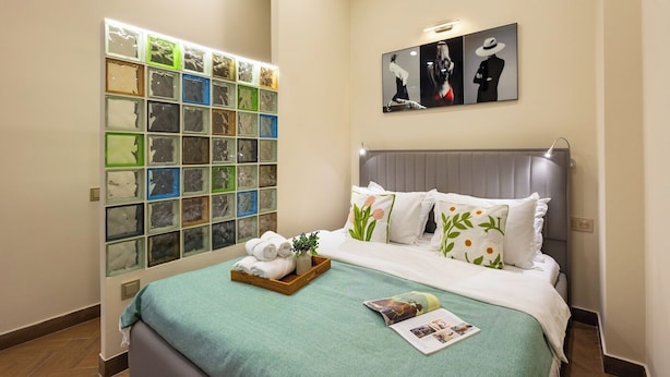 Une chambre d’hôtel avec un lit, un mur composé de panneaux de verre décoratifs et une œuvre d’art encadrée au-dessus du lit.
