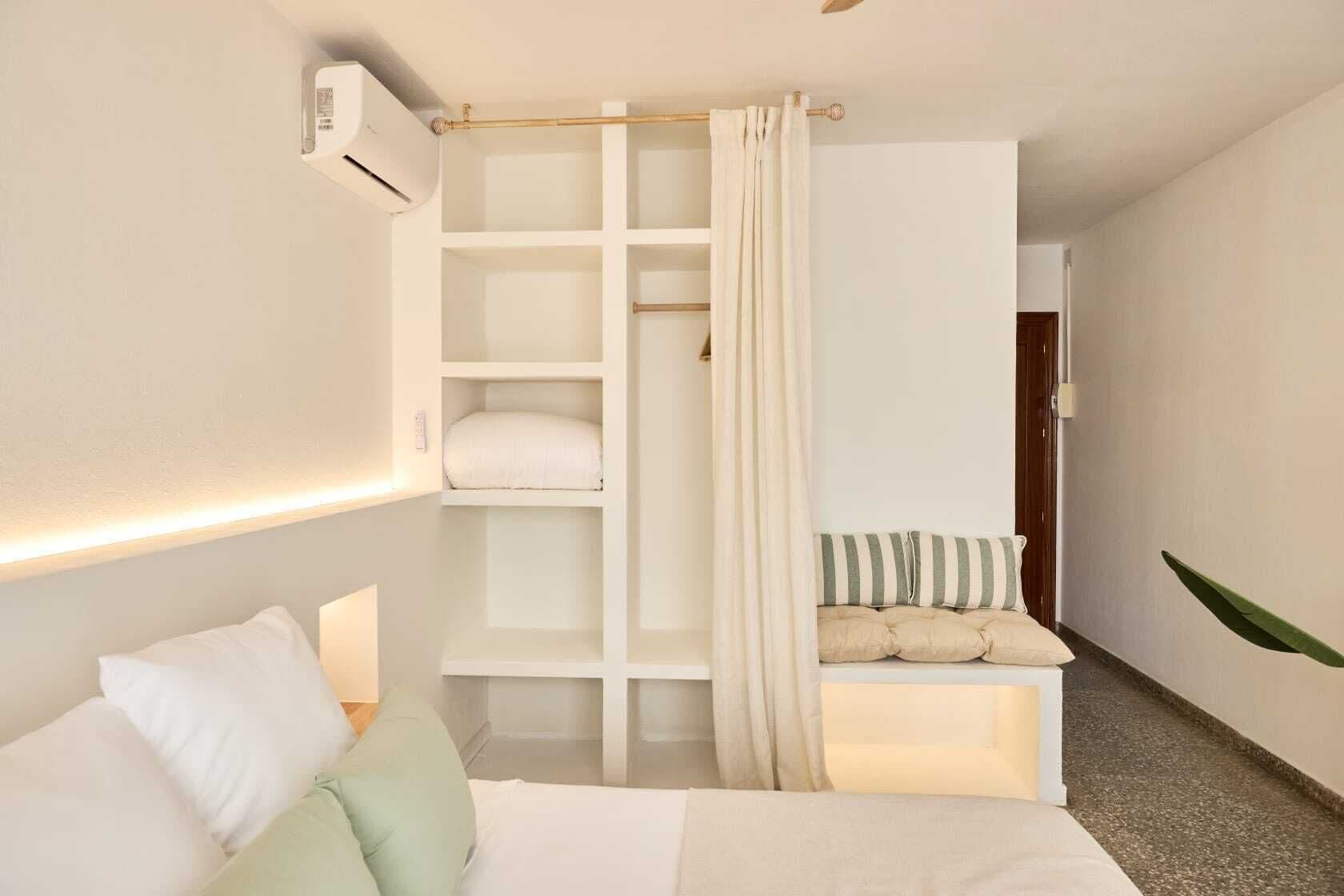 Un dormitorio con cama, armario empotrado, mesita de noche y una planta colgante.