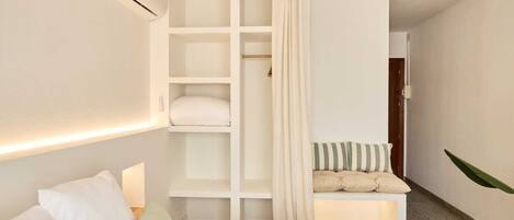 Un dormitorio con cama, armario empotrado, mesita de noche y una planta colgante.