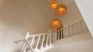 A staircase with white balusters and a handrail, leading to a landing with a sofa and a patterned rug.