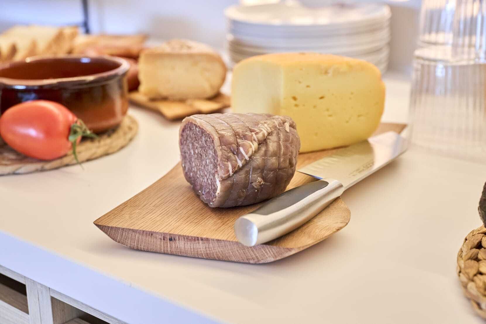 Una tabla de quesos con distintos tipos de queso y un cuchillo sobre una tabla de madera.