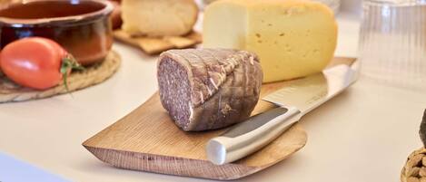 Una tabla de quesos con distintos tipos de queso y un cuchillo sobre una tabla de madera.
