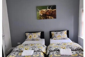 Una stanza con due letti, ognuno con biancheria a motivi floreali e un quadro di un toro appeso al muro.