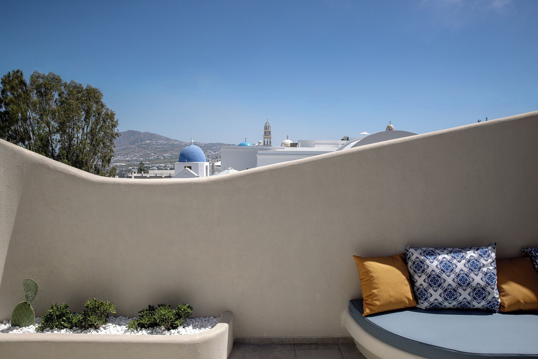 Un balcón con vista a un paisaje urbano, que incluye una torre de reloj y edificios con cúpulas.