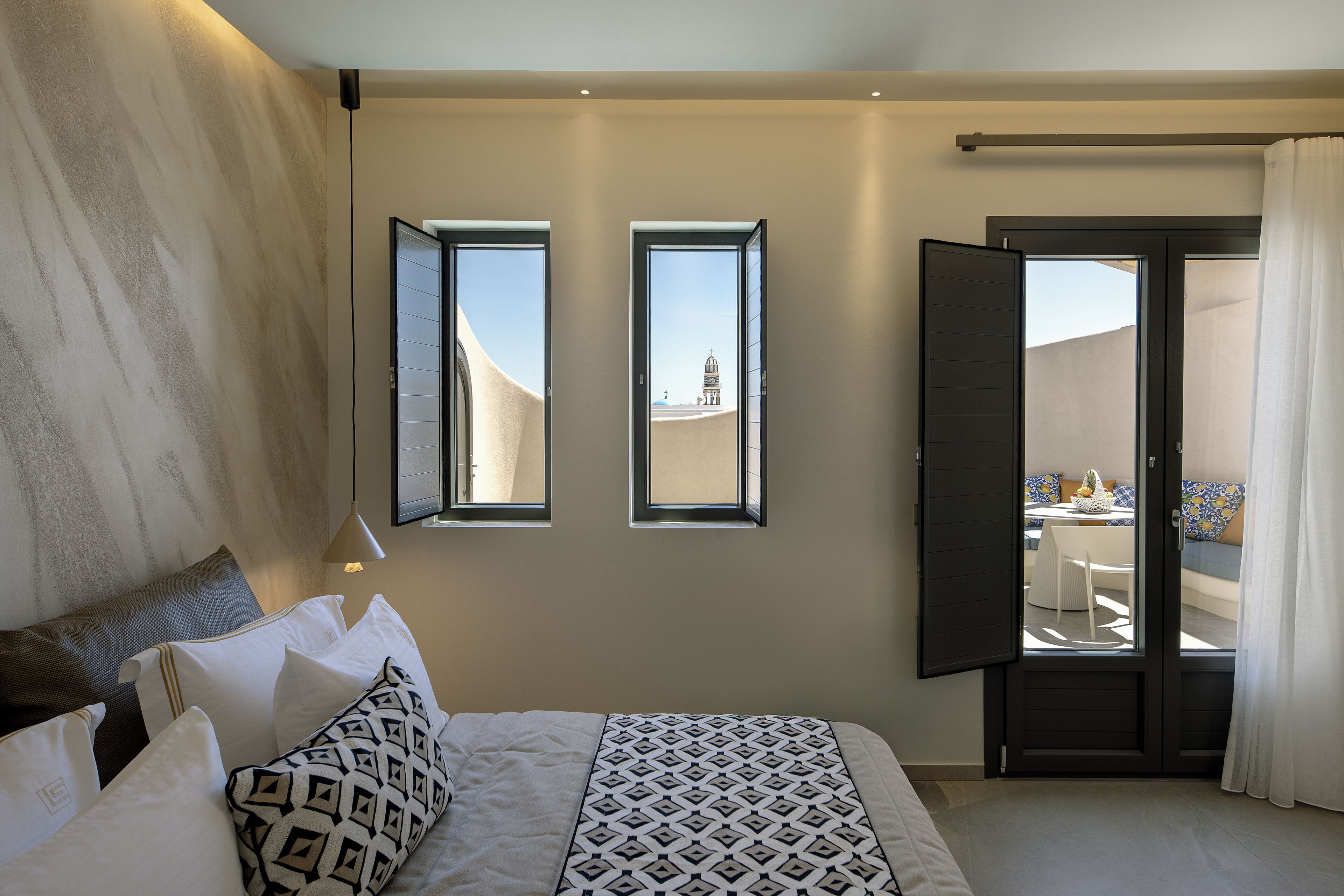 Un dormitorio con cama, almohadas, una ventana y una puerta que da a un espacio exterior.
