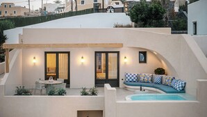 A modern outdoor living area with a curved sofa, a dining table, and a small pool. - La Madeleine Suites Fira (Santorini)