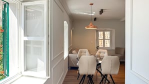 Een eetgedeelte met een tafel en stoelen, een raam met uitzicht en een hanglamp.